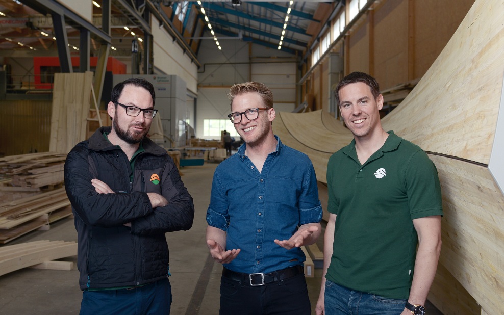 Groupe de personnes en reconversion dans la halle de production avec un objet en bois en arrière-plan