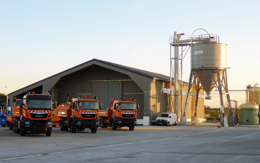 Installation complète à Fahrbinde (Allemagne), composée d’un entrepôt, d’un silo en bois et d’une centrale à saumure, devant lesquels sont stationnés trois camions du service hivernal