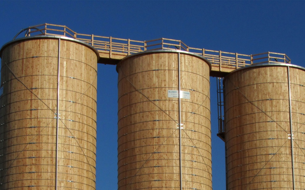 Drei runde Holzsilos mit Dachpodeste aus Holz und Dachübergängen verbunden