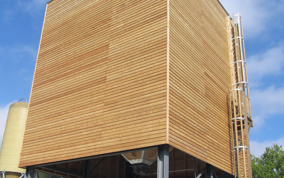 Silo modulaire en bois de 350 m³ avec support en acier gris et échelle en bois, petit silo en plastique en arrière-plan