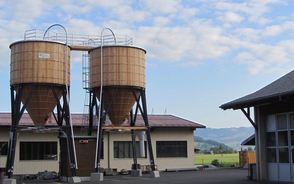 Zwei runde 100 m³ Silos aus Holz mit Stahlleiter und Dachpodium aus Stahl auf Werkhofareal platziert