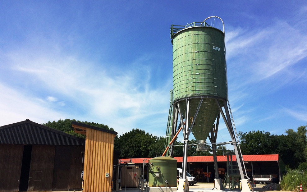 Grüner runder 250 m³ Silo aus Holz auf Stahlunterbau auf einem Werkhof platziert