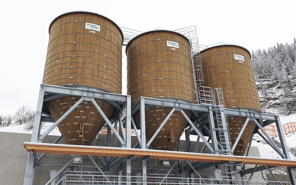 Drei runde Streugutsilos aus Holz für die Lagerung von Salz und Splitt in Zernez