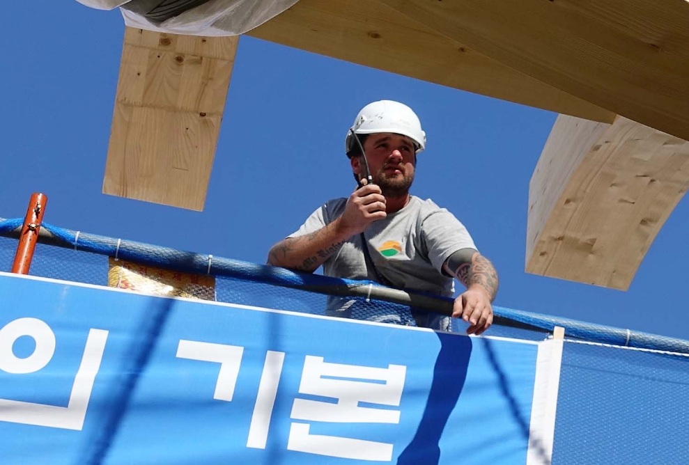Zimmermann-Monteur auf einer internationalen Baustelle mit dem Funkgerät in der Hand