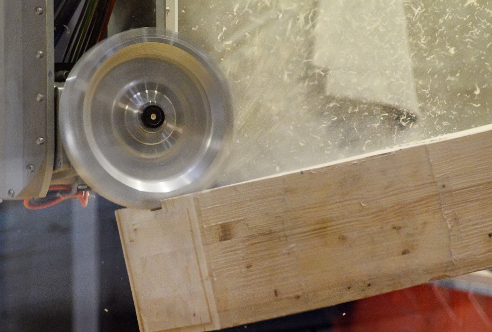 The milling head processes the piece of wood on the CNC machine. The shavings fly off.
