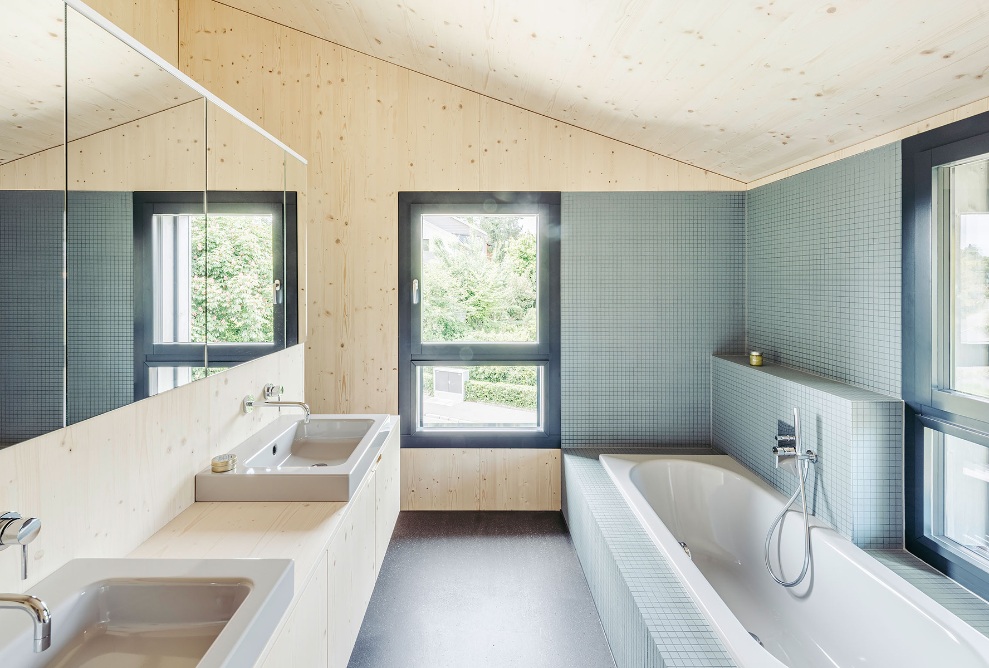 Vue de la salle de bains avec baignoire d’un côté et lavabo double vasque de l’autre. 