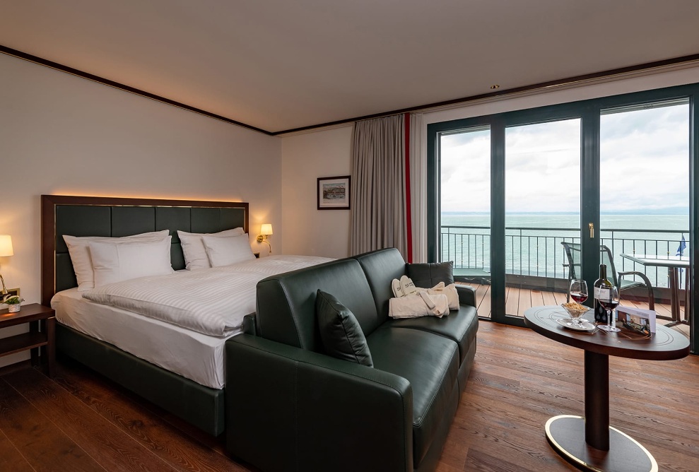 Blick ins Hotelzimmer mit Doppelbett, grosser Fensterfront und Balkon mit Sicht auf den Bodensee