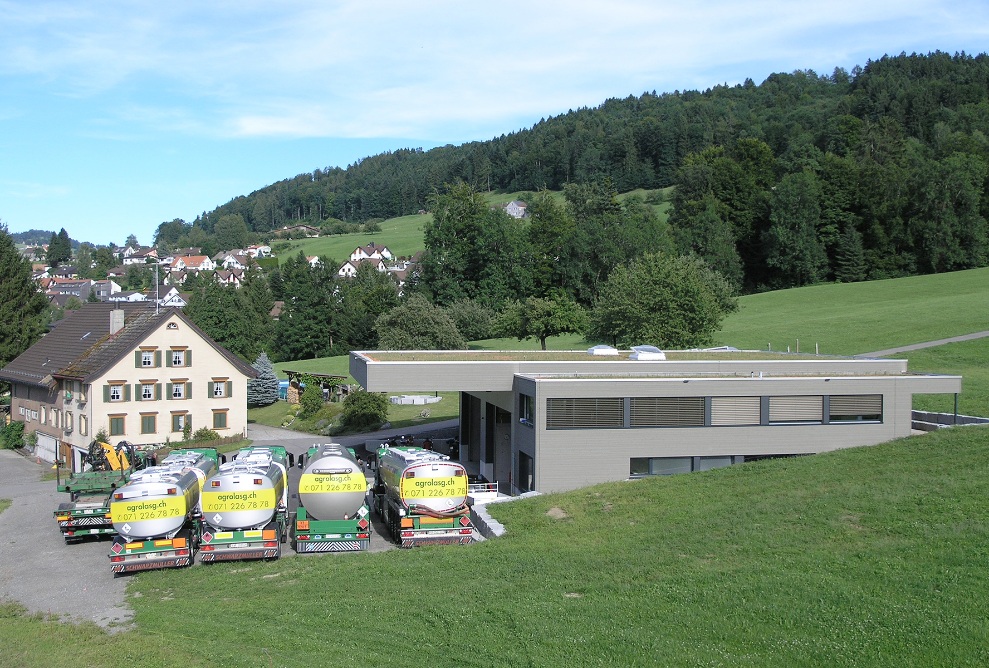 Overall picture from afar: lorry garage from the side and font with the lorry fleet in front.