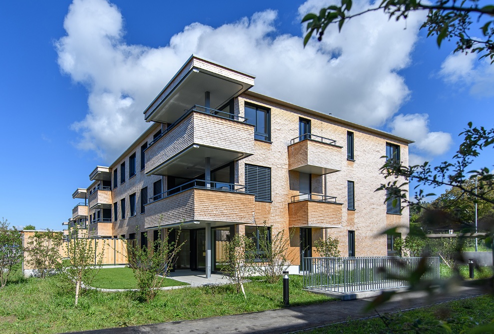 Ein Mehrfamilienhaus, welches die Elemente Holz und Glas miteinander vereint.