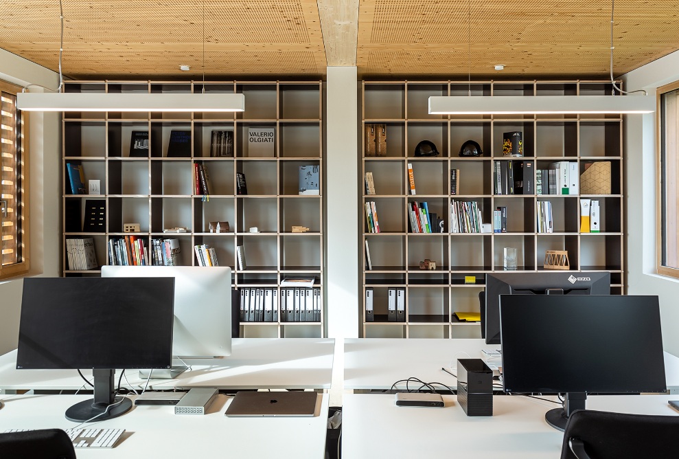 Quatre postes de travail et un mur de livres dans le bureau.