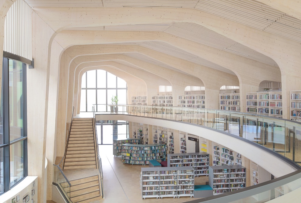 Blick von der Galerie in den grossen, hellen Raum mit Treppe und Bücherregalen 
