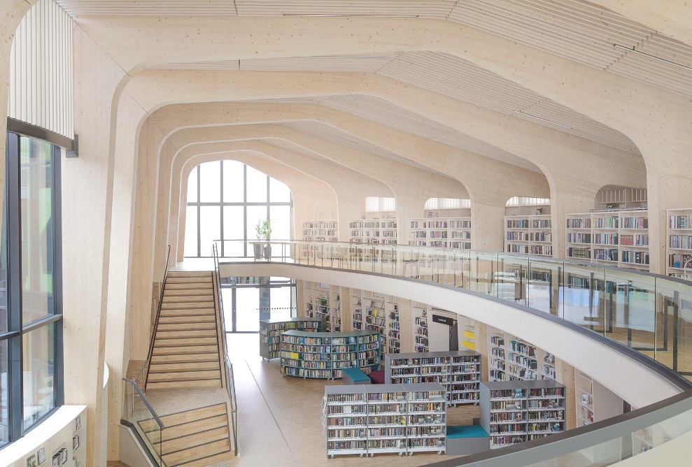 Vue depuis la galerie dans la grande salle lumineuse avec escalier et étagères à livres 