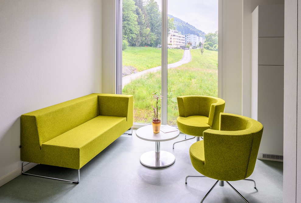 Detailansicht der Sitzecke mit grünem Sofa und zwei grünen Sesseln im Schulhaus Grenzhof Luzern