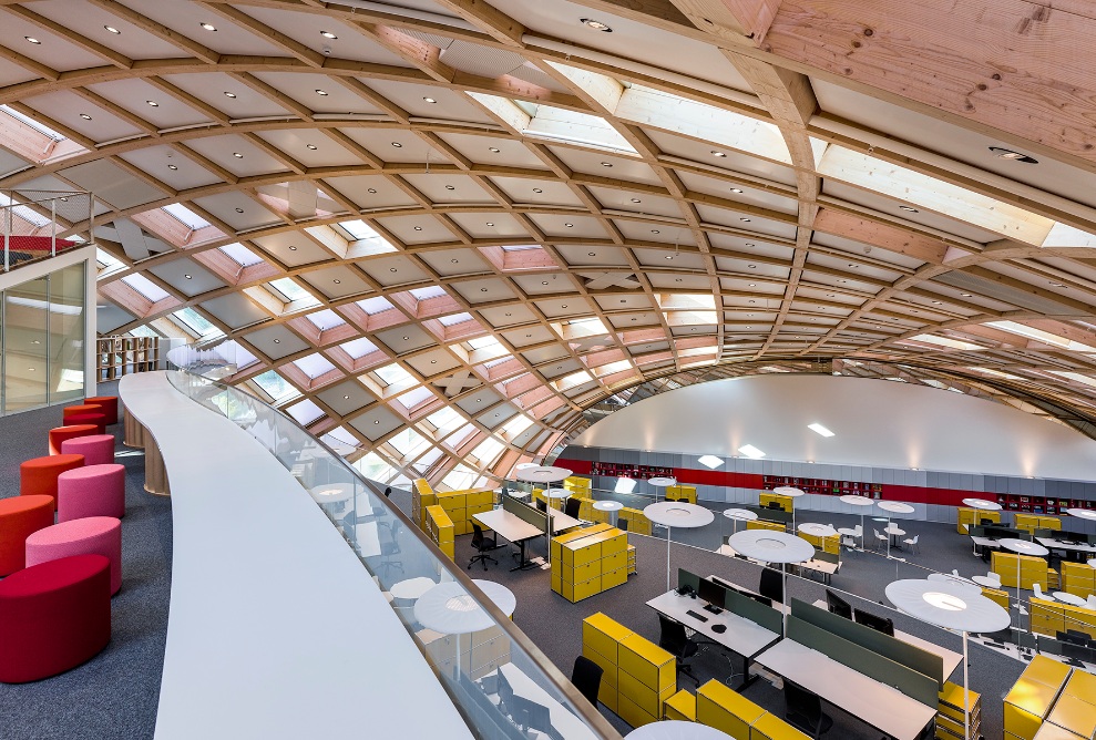 Vue depuis la galerie sur les postes de travail dans les bureaux du bâtiment Swatch. La construction grillagée en bois du plafond est visible à l’intérieur.