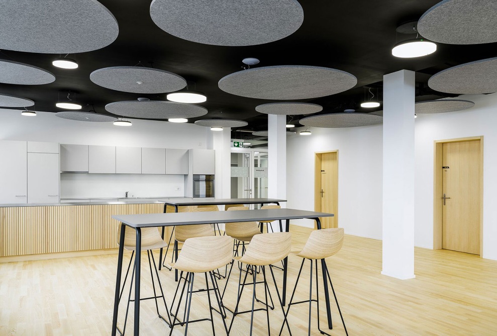 Mit Holz ausgekleideter Raum im Ärztezentrum mit Hochtisch und Küchenzeile
