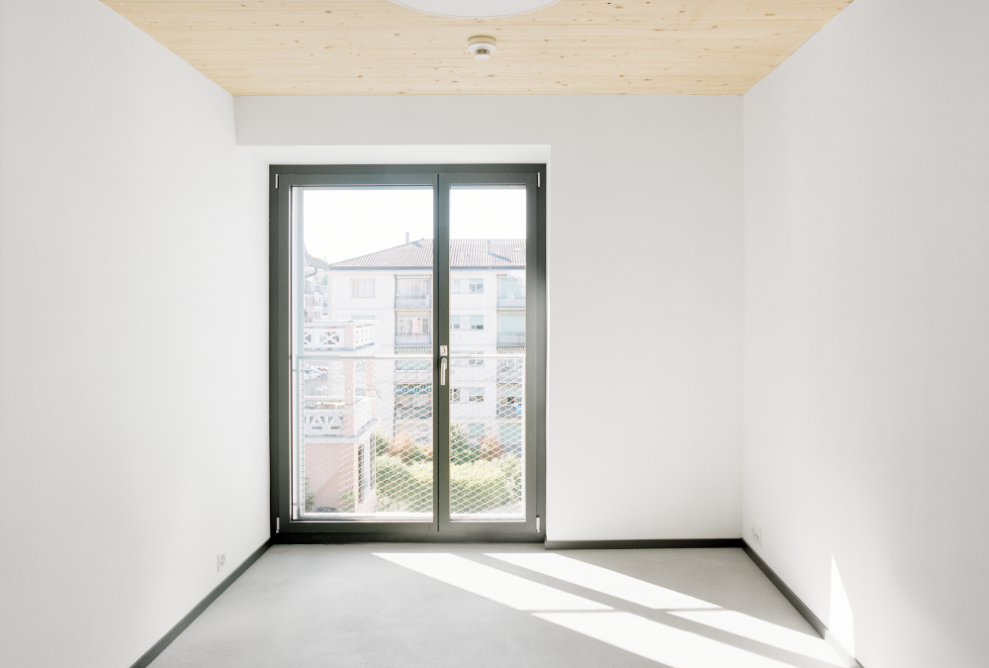 Bright double room with timber ceiling and large, floor-to-ceiling window