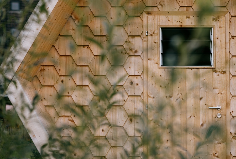 Vue détaillée de la porte d’entrée en bois et de la façade avec bardeaux en bois en forme d’alvéoles 