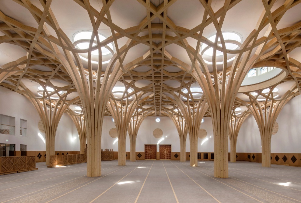 Baumartige Tragstruktur aus Holz und orientalische Holzelemente an Wänden und Türen im Innenbereich der Cambridge Mosque.