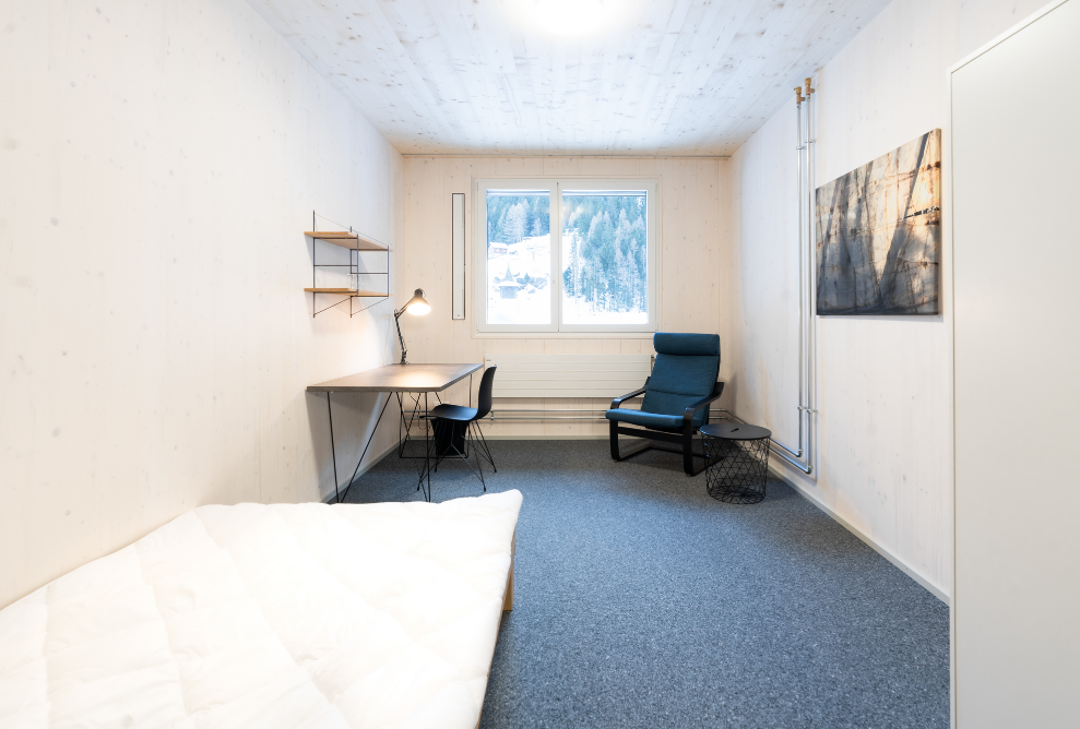 Interior view of a single room in the Dammastock modular timber building.