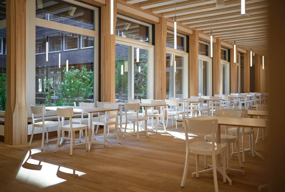 Moderner Speisebereich im Hortus mit Holzträgern, grossen Fenstern und weissen Stühlen