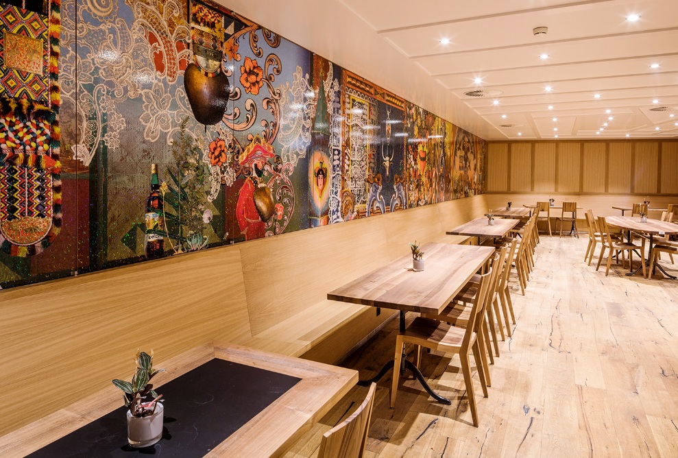 Hotel Säntis dining area with wooden furnishings. The walls are decorated with traditional Swiss imagery.