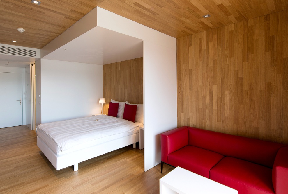 Le sol, les murs et le plafond de cette chambre de l’hôtel Säntispark sont revêtus du même bois. La chambre lumineuse est équipée d’un mobilier moderne.