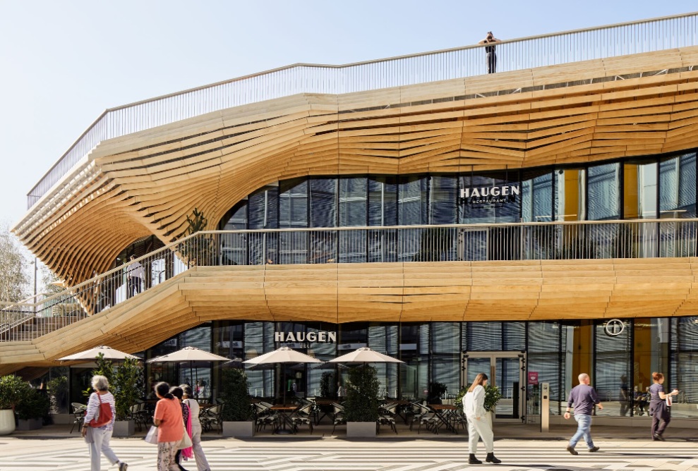 Facade of the IQL Pavilion with lots of glass and terraces made of timber