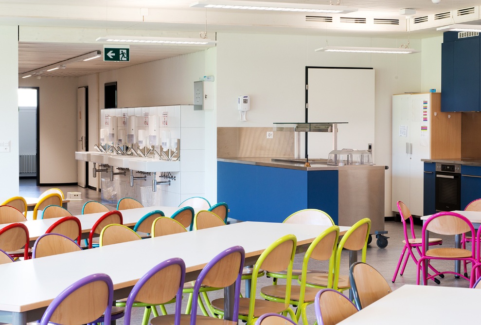 On voit la cuisine avec coin repas et lavabos supplémentaires dans un jardin d’enfants à construction modulaire