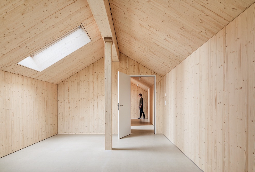 Pièce lumineuse entièrement en bois, avec toit incliné et lucarne dans un appartement de l’immeuble résidentiel Quellenhof