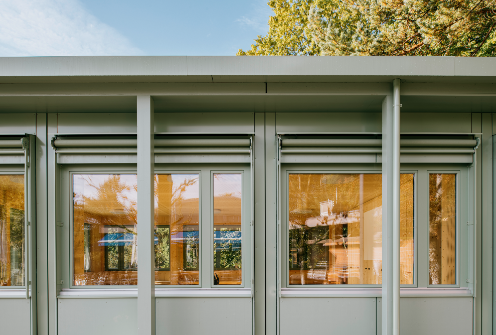 Part of the light-green pavilion facade with windows