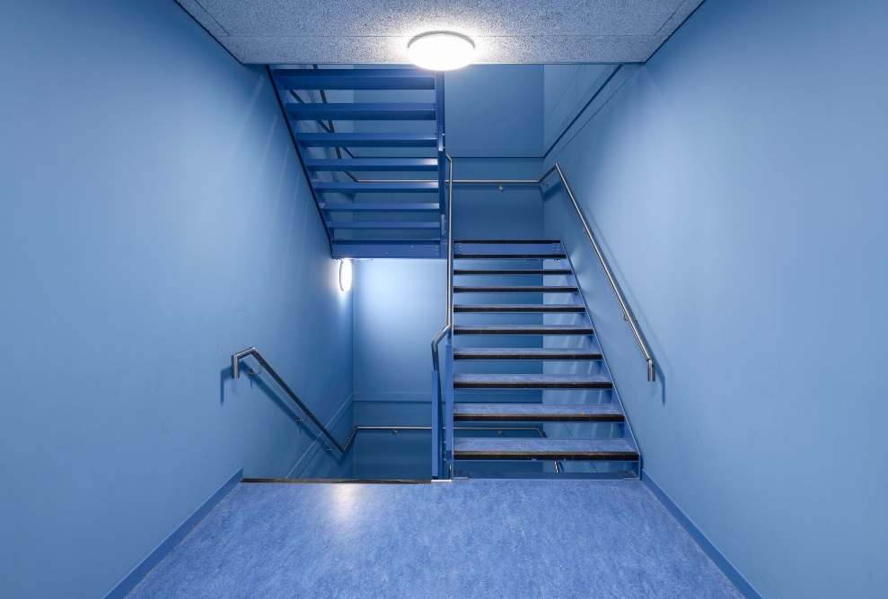 Modern stairwell with blue walls and steel railing in school building