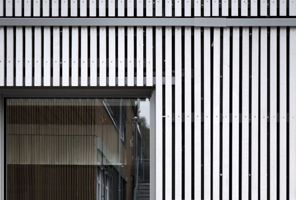 Graue Fassade des Schulmodulbaus mit vertikalen Holzleisten