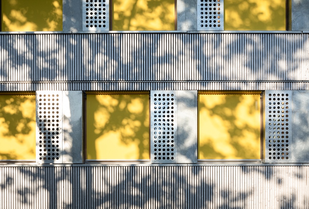 Holzfassade des Schulpavillons Brünnen mit gelben Rollläden