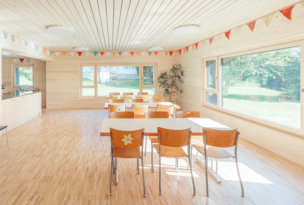 Vue intérieure d’une salle lumineuse en bois clair avec table et chaises