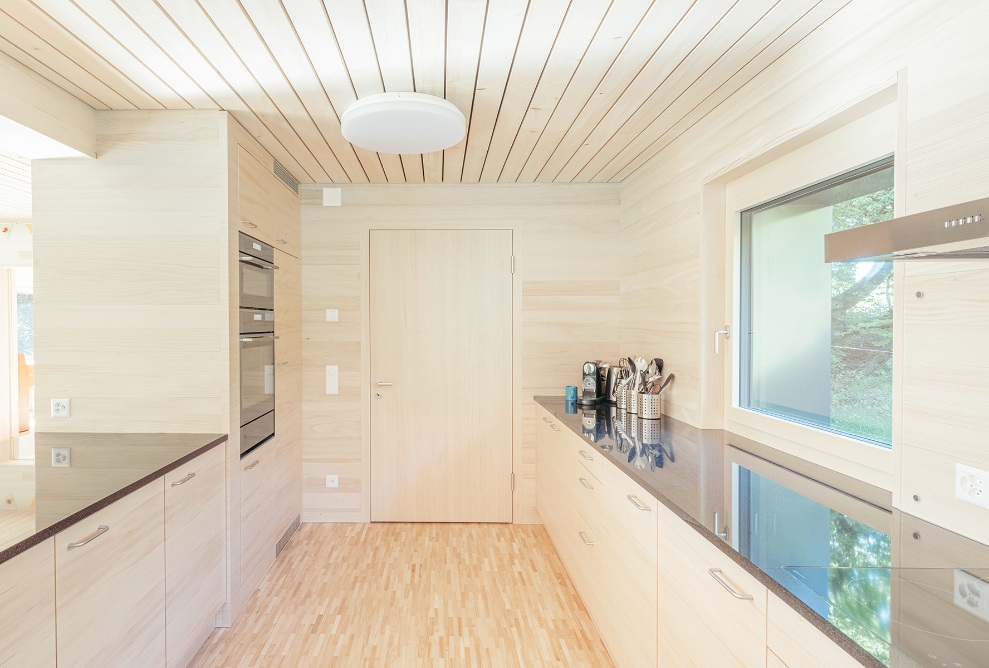 Overall view of the bright kitchen with dark worktops and wooden cabinet fronts