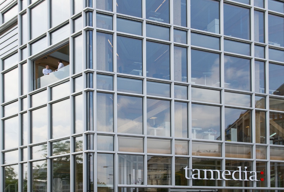 Glazed facade of the new Tamedia office building with view of the wooden support structure