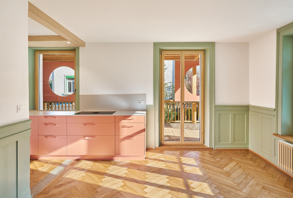 Farbig lackierte Küche mit Holz-Fussboden und grünen Innenausbau-Elementen