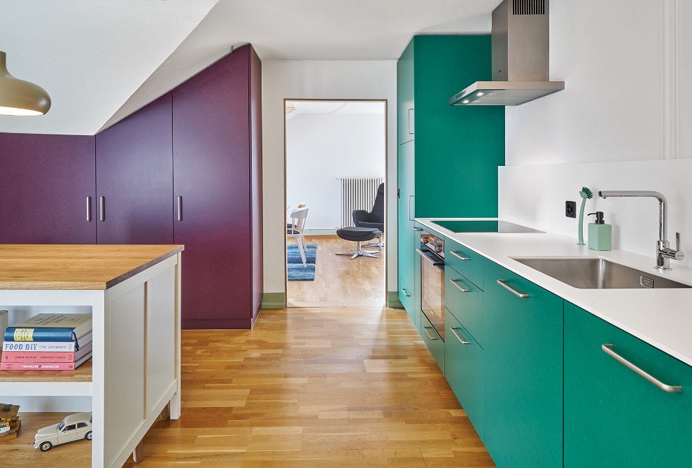 Fitted kitchen with cupboard doors in an accenting colour and wooden floor