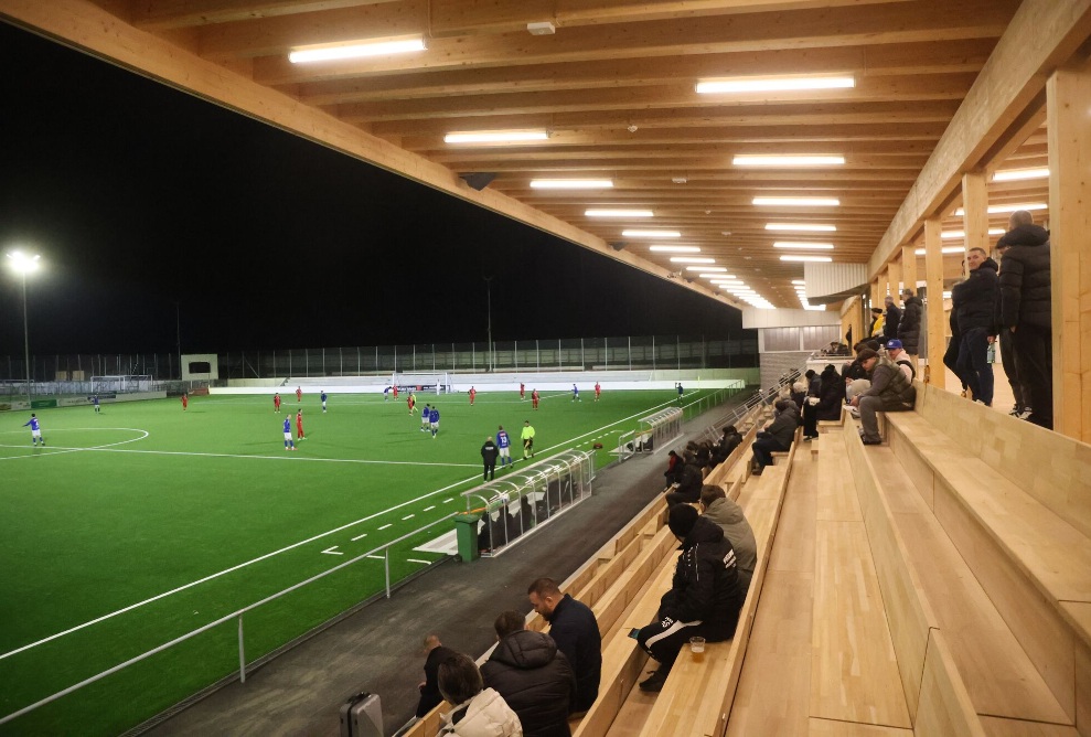 Zuschauer auf der neuen Holztribüne mit Blick auf das abendliche Fussballspiel in Gossau