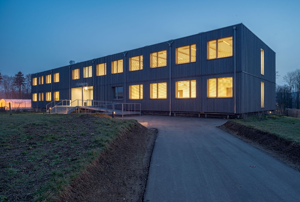 The University of Lausanne temporary office building at night.