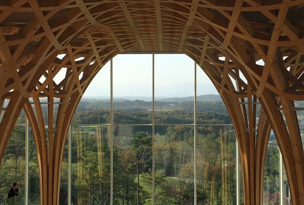 View of the golf course from the entrance through the windows opposite. The wooden supporting structure dominates the space.