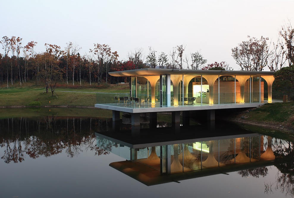 View of the illuminated lakeside pavilion at dusk.