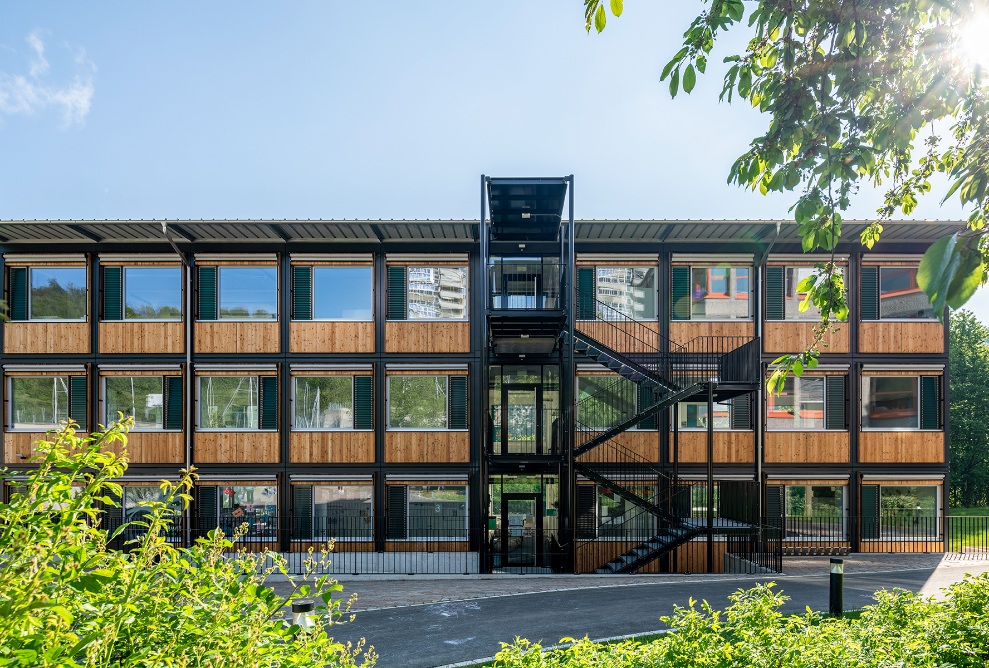 Gesamtansicht des ZM10-Schulpavillons Sihlweid in Zürich frontal von vorne, mit Pflanzen im Vordergrund